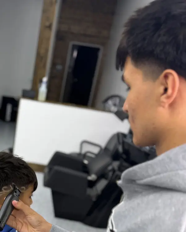 Ibrahim cutting a young client's hair